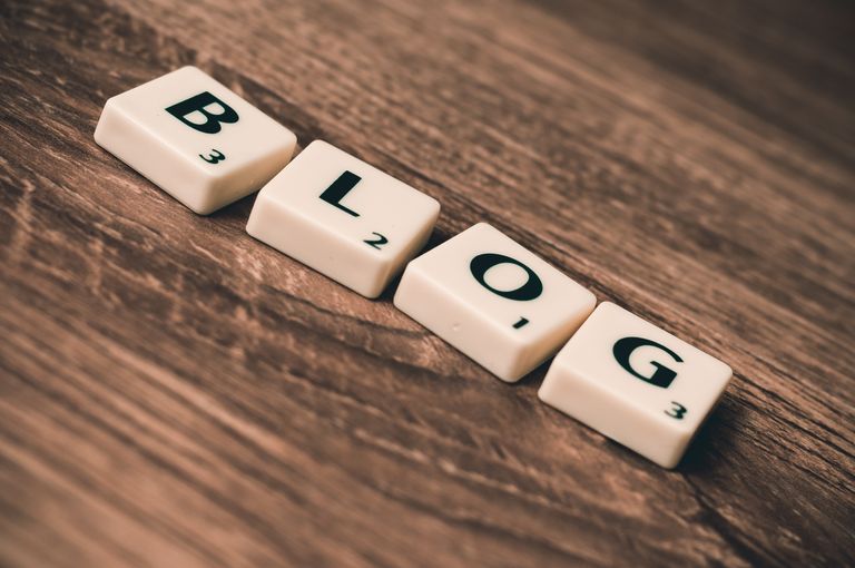 UploadBlog.com Online Posting Scrabble tiles spelling 'BLOG' on a wooden background, symbolizing creativity and writing.