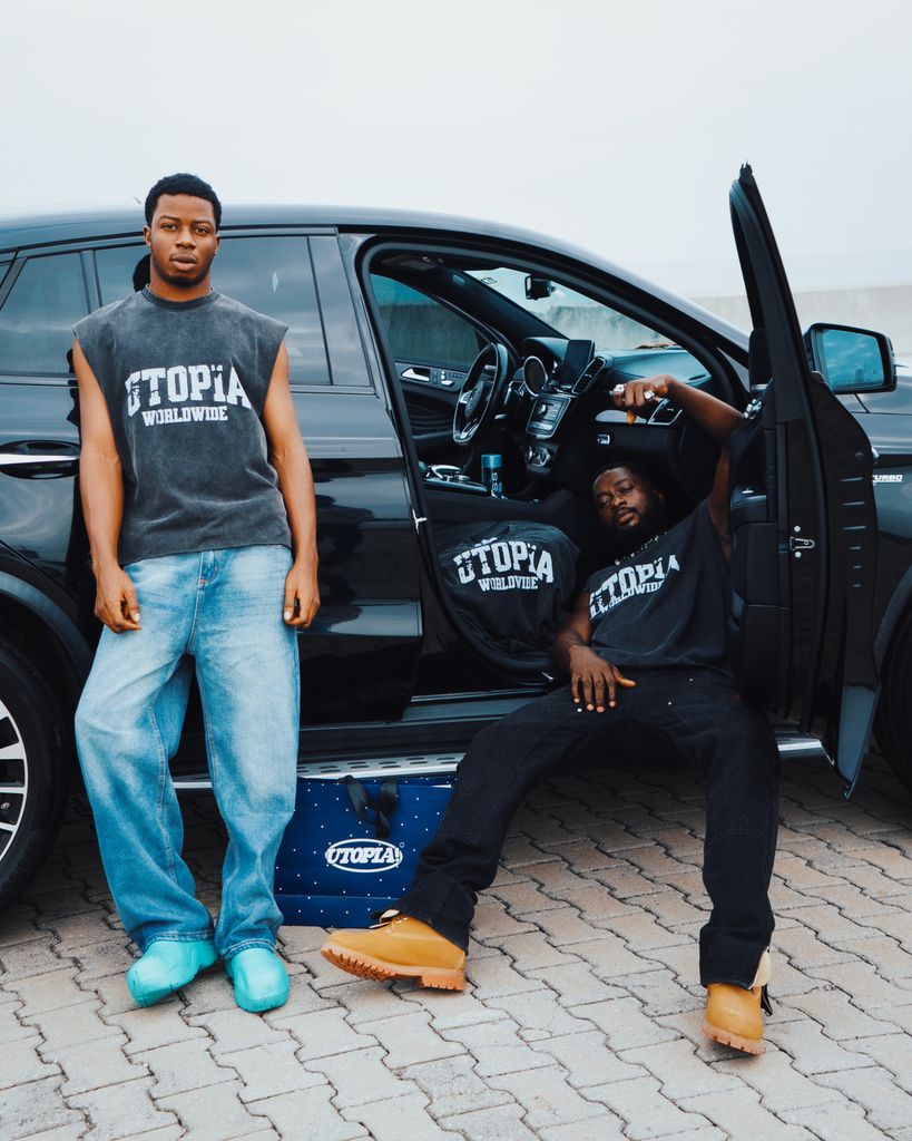 TheUploadArticleBlog.com Stylish young men pose by a black SUV in casual fashion outfits.